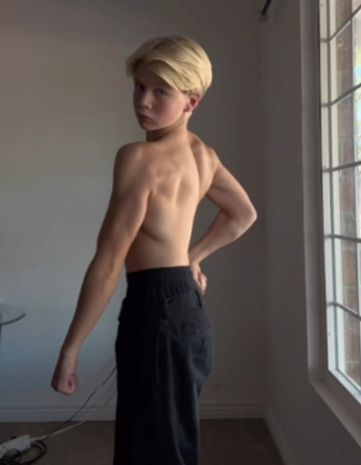 A young blond boy without a shirt showing off his back muscles.